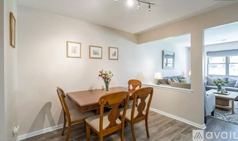 A dining room with a table set for two and a view of the living room.
