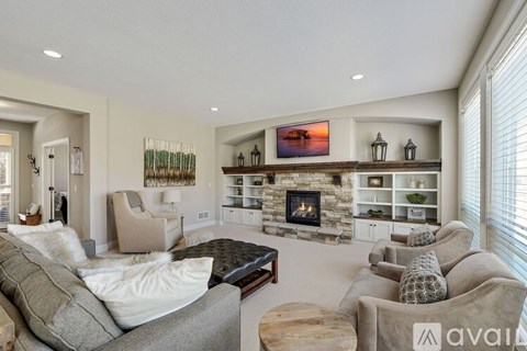 A living room with a grey couch, a black coffee table, and a fireplace with a painting above it.