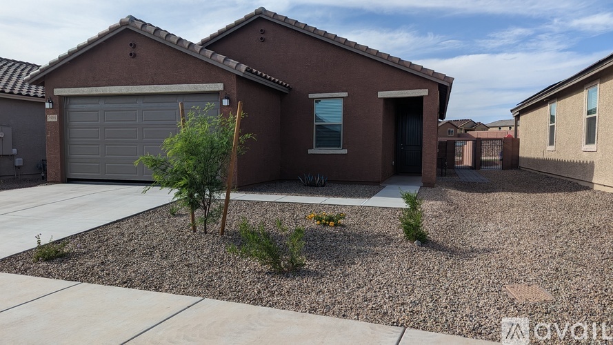 A house with a brown roof and a gravel driveway.
