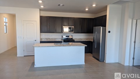 A kitchen with a white island and black cabinets.