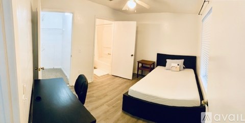 A bedroom with a bed, desk, and chair.