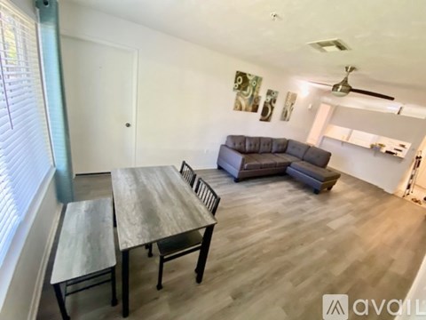 A living room with a grey couch and a wooden dining table.