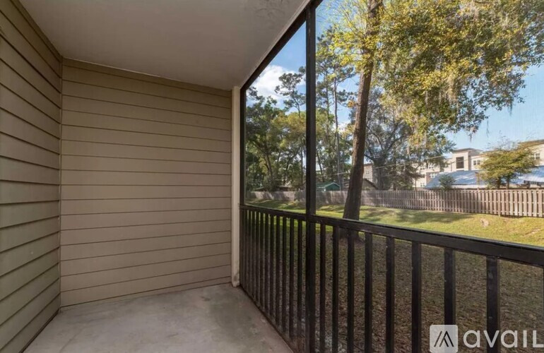 A balcony with a black railing and a view of a tree and a building.