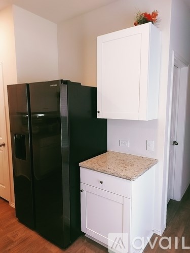 A black refrigerator and a black freezer are in a kitchen with a white cabinet and a granite countertop.