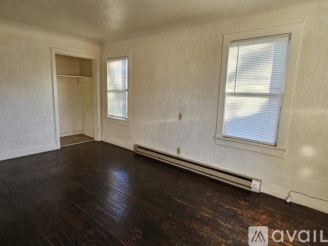 A room with wooden floors and two windows.