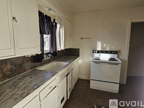 A kitchen with a white stove and cabinets.