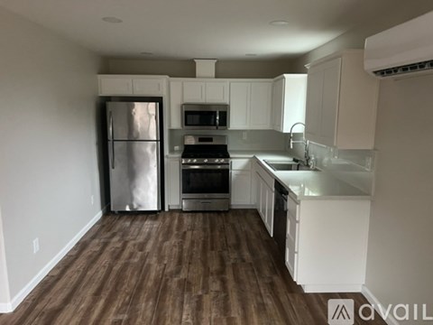 A kitchen with white cabinets and a wooden floor.