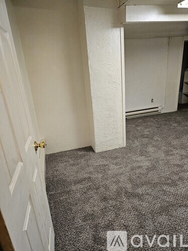 A small, empty room with a carpeted floor and a white wall.