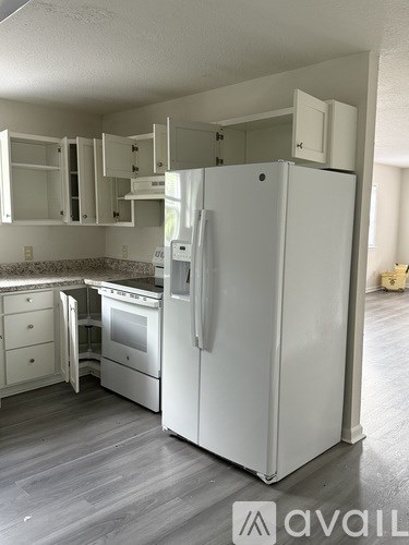 A white refrigerator stands in a kitchen with a countertop and cabinets.