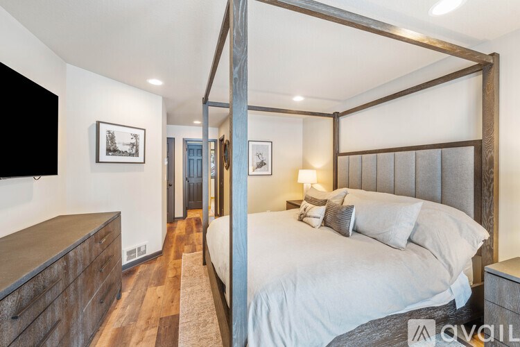 A bedroom with a four poster bed and a wooden dresser.