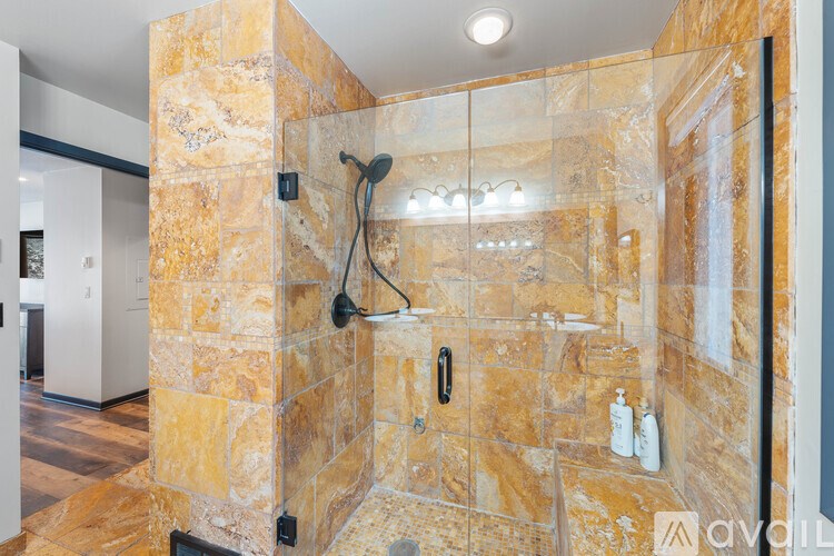 A bathroom with a stone wall and a glass shower door.