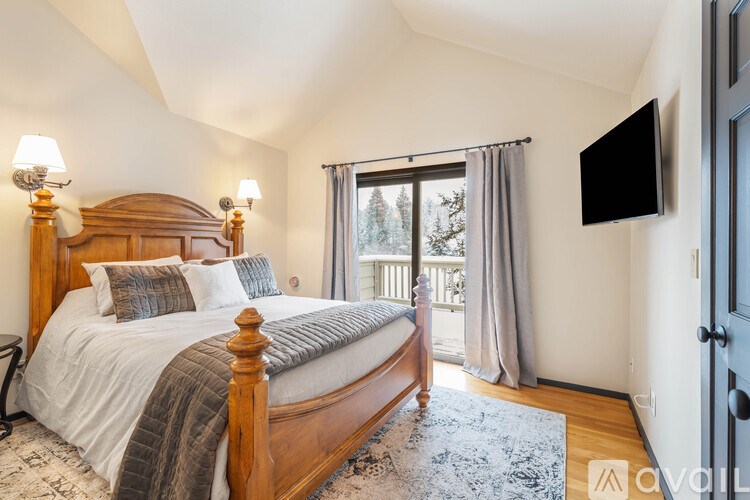 A bedroom with a large bed and a flat screen TV mounted on the wall.