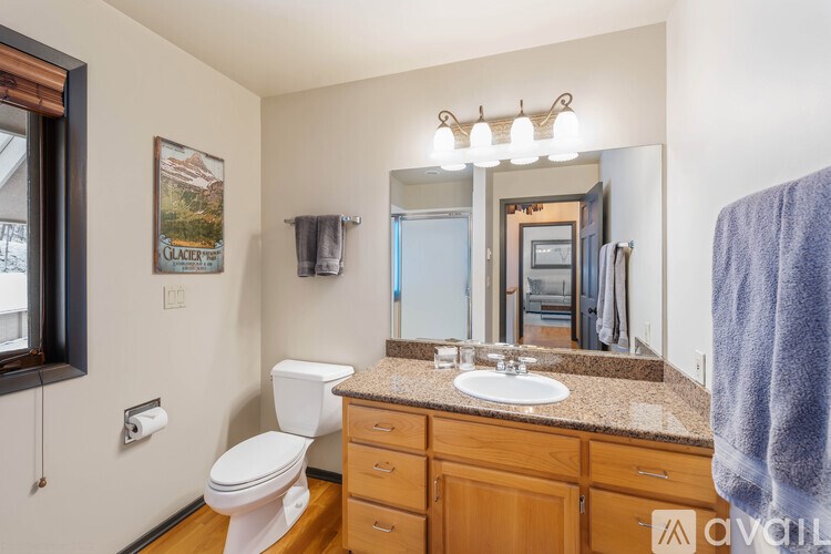 A bathroom with a toilet, sink, and mirror.