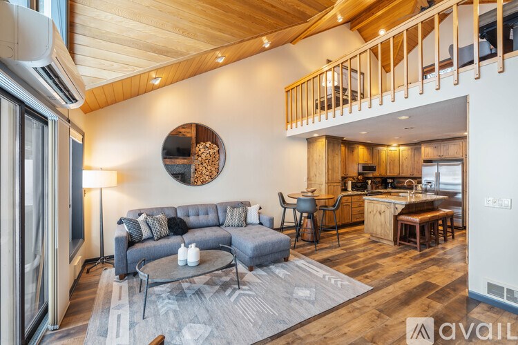 A modern living room with a grey sofa and a round mirror on the wall.