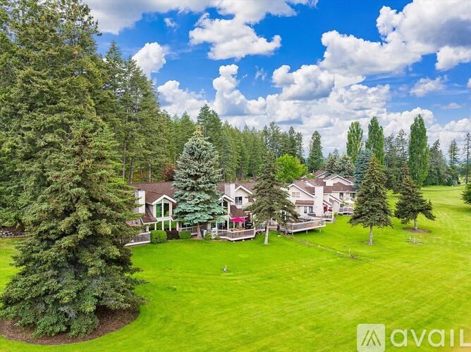 A large house surrounded by trees and a green lawn.