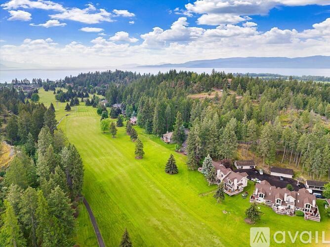 A bird's eye view of a large grassy area surrounded by trees with a few houses in the distance.