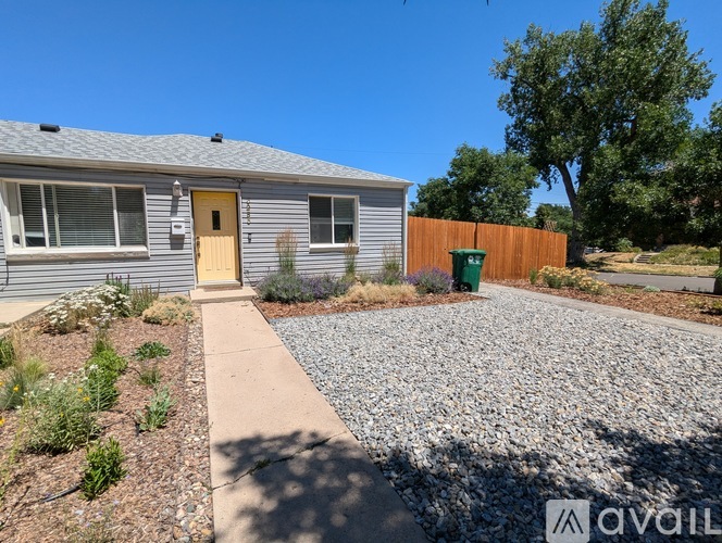 A house with a yellow door and a gravel driveway.