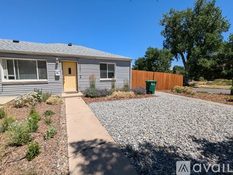 A house with a yellow door and a gravel driveway.