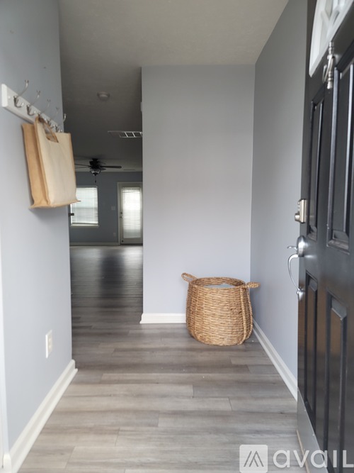 A hallway with a basket on the floor and a black door on the right.