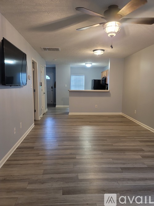 A spacious room with wooden flooring and a ceiling fan.