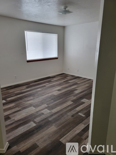A room with wooden flooring and a window with blinds.