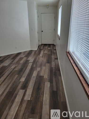 A hallway with wooden flooring and a white door.