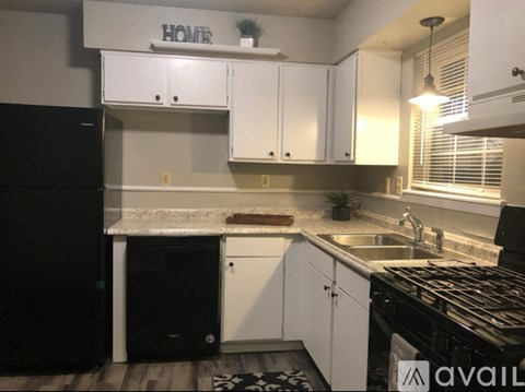 A kitchen with white cabinets and a black fridge.