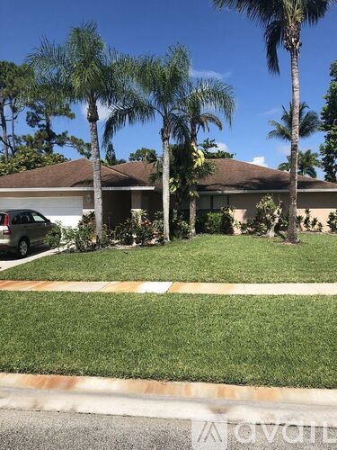 A house with a brown roof and a white car parked in front.