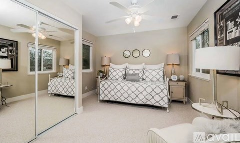 A bedroom with a bed, nightstand, and a ceiling fan.