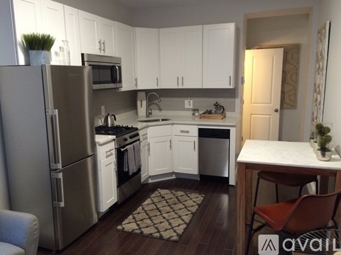 A kitchen with white cabinets and a stainless steel refrigerator.
