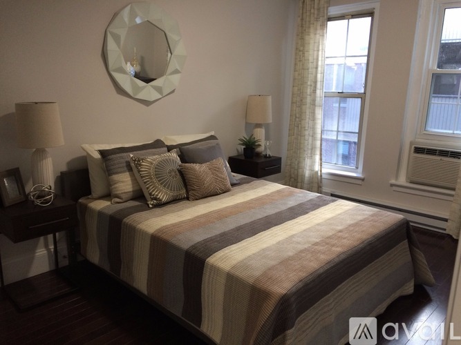 A bedroom with a bed, two lamps, and a mirror on the wall.