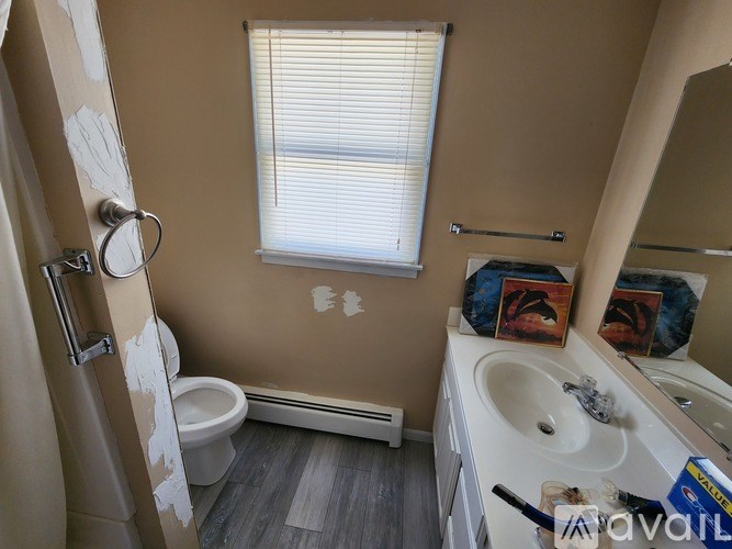 A bathroom with a toilet, sink, and mirror.