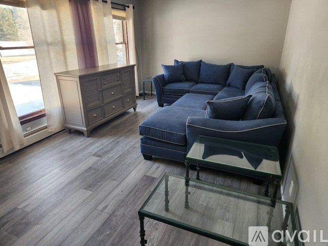 A living room with a blue couch and a glass coffee table.