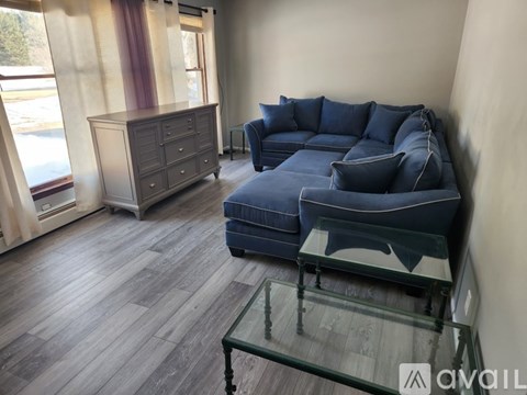 A living room with a blue couch and a glass coffee table.