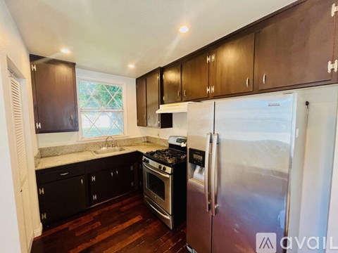 A kitchen with dark wood cabinets and a stainless steel refrigerator.