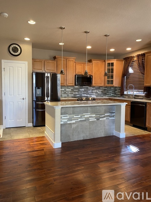 A kitchen with wooden floors and a stone counter.