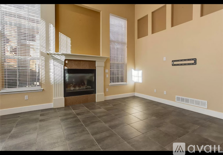 A living room with a fireplace and a large window with blinds.