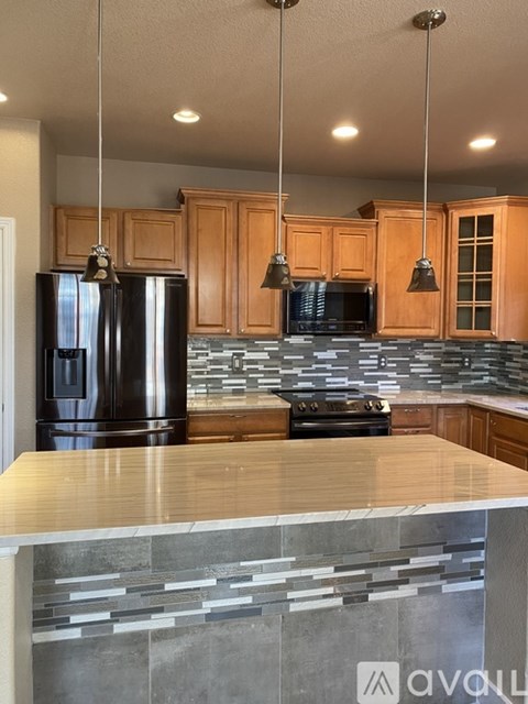 A kitchen with wooden cabinets and a black refrigerator.