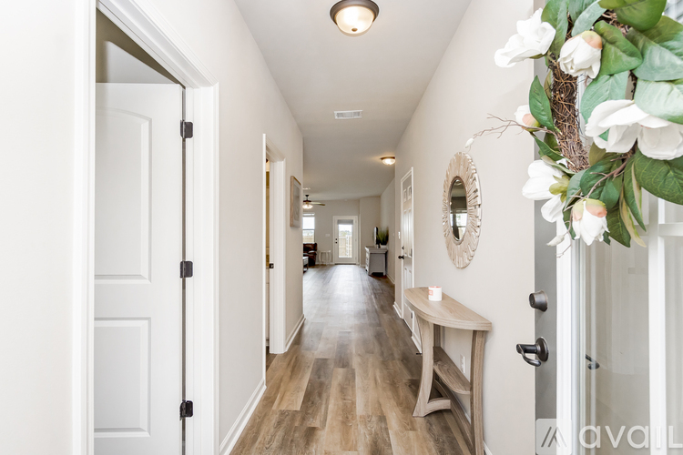 A hallway with a bench and a flower arrangement on the door.