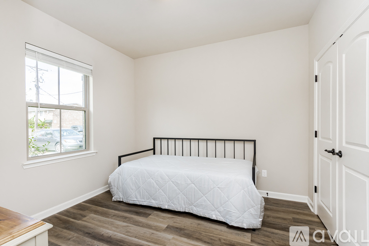 A bedroom with a white bed and wooden flooring.
