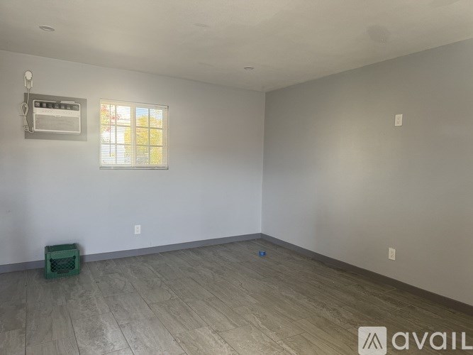 A room with a window and a wooden floor.
