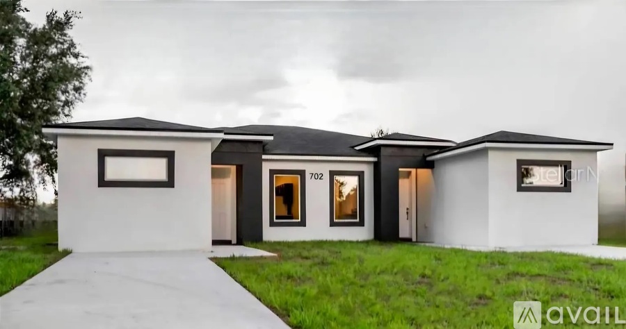 A modern house with a white exterior and a black roof is available for purchase.