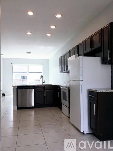 A kitchen with black cabinets and a white refrigerator.