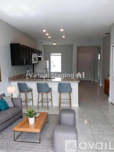 A living room with a grey couch, a wooden coffee table, and a bar area with stools.