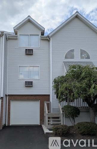 A two-story house with a garage and a tree in front.