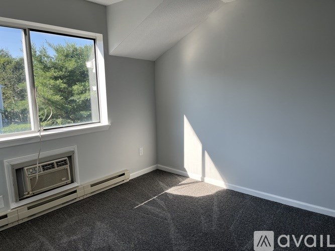 A room with a fireplace and a window overlooking trees.