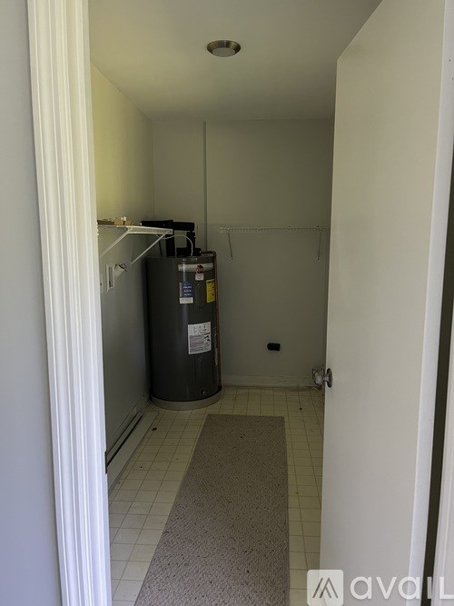 A small, empty room with a trash can and a white door.