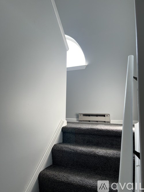 A staircase with a light on the side and a box on the floor.