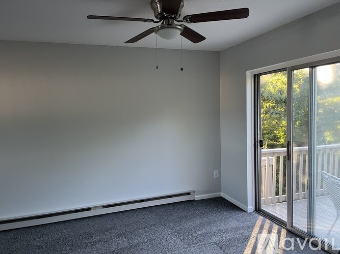 A room with a ceiling fan and sliding glass doors leading to a balcony.