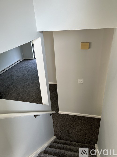 A staircase with a carpeted runner and a wall-mounted light fixture.